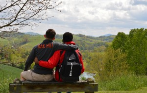 Two students, pictured from behind, with arms around each other, looking out over the mountains