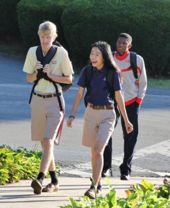 Three students in oak hill academy clothing walk together on campus