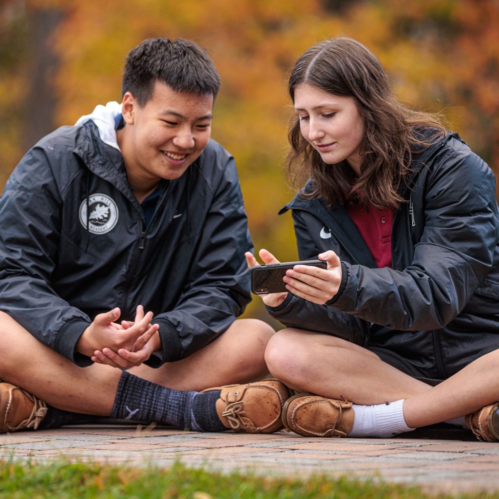 students sitting together looking at phone