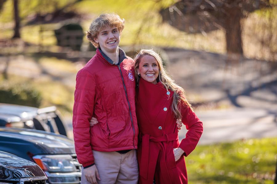 A mother and son in red jackets embrace on Oak Hill campus