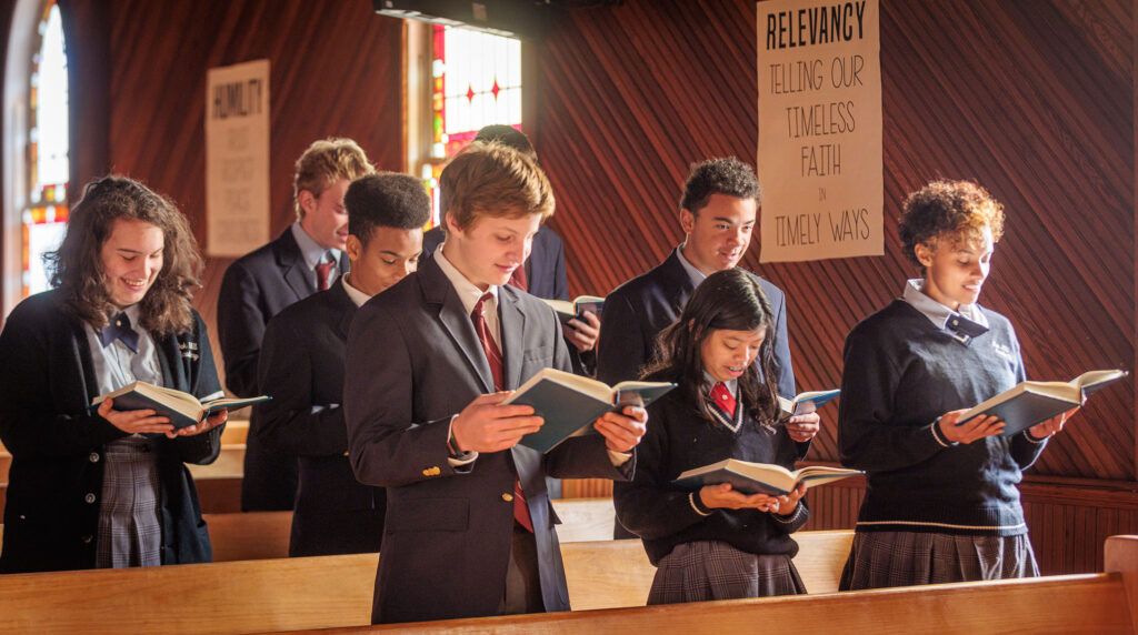 Students singing from a hymnal during a church service.